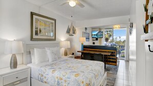 Quarto de hotel com cama, mesas de cabeceira, escrivaninha e varanda com vista.