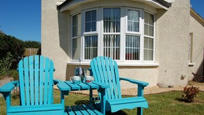 A two-seater table with chairs in front of a house with a bay window. - Angorfa Family Holiday Home with Games Room (Tywyn)