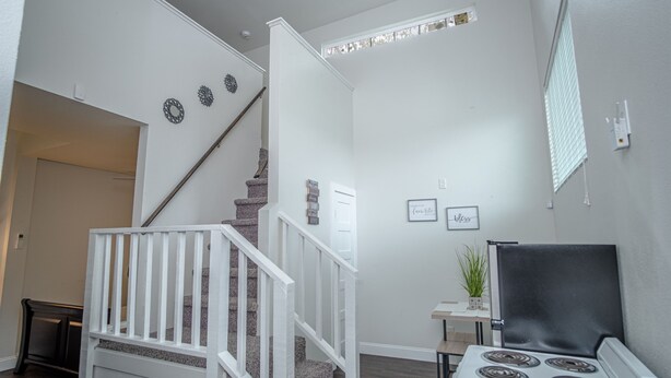 Eine Küche mit einem weißen Herd, einem kleinen Tisch mit einer Pflanze und einer Treppe mit weißen Geländern.