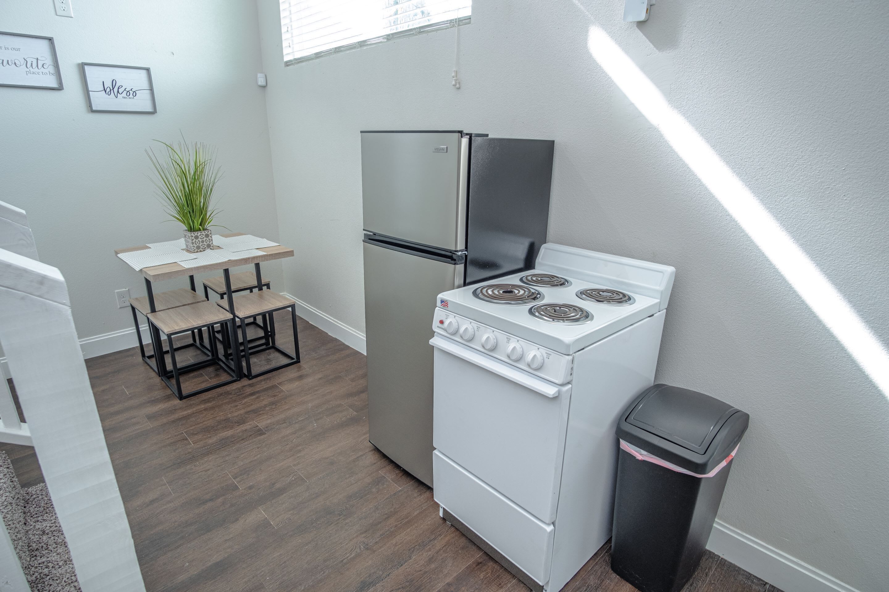 A compact kitchen with a refrigerator, stove, and a small dining table with chairs.