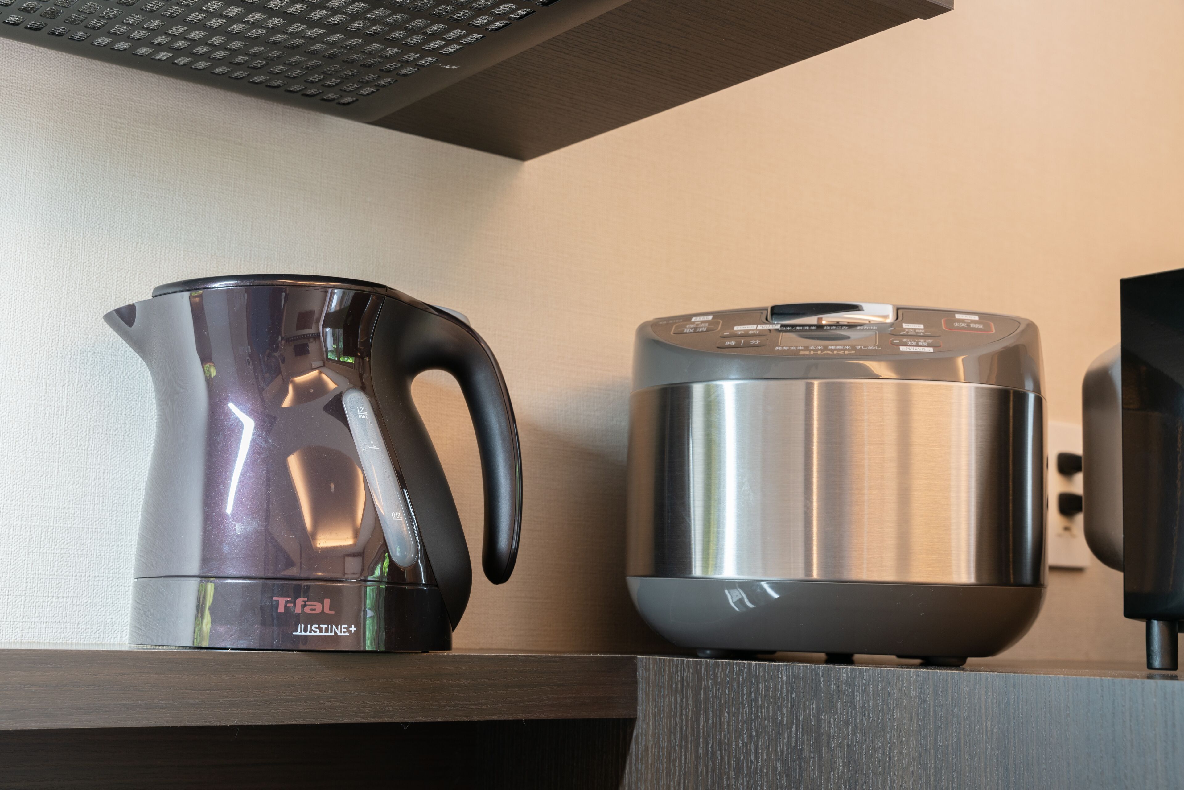 A stainless steel kettle and a coffee maker on a wooden shelf.