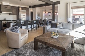 Relax in a cozy seating area with a plush sofa and armchair, complemented by a coffee table. Enjoy a functional kitchen with a central island and bar stools.