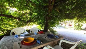 Une table de jardin avec des chaises, des assiettes, des bols et des couverts.