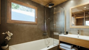 A modern bathroom with a glass-enclosed shower, a large bathtub, a wooden vanity with a mirror, and a potted orchid. - 4★ Chalet, 8 pers, cozy, near slopes, La Clusaz (La Clusaz)