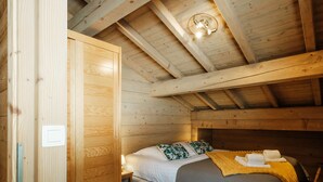 A wooden cabin bedroom with a bed, pillows, a bedside table, and a ceiling light fixture. - 4★ Chalet, 8 pers, cozy, near slopes, La Clusaz (La Clusaz)