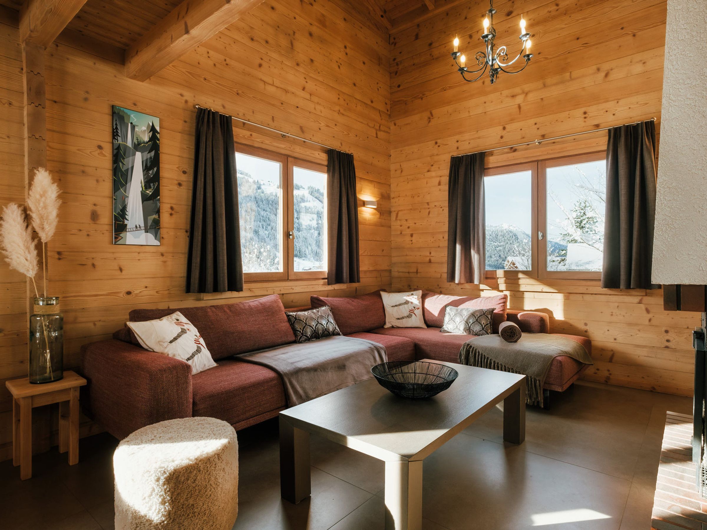 Een knus houten blokhut interieur met een hoekbank, een eettafel en een kroonluchter.