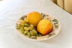 Un plato con una naranja, un melocotón y uvas sobre un mantel con estampado floral.