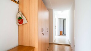 Um corredor com piso de madeira, um banco de madeira e um porta-roupas com uma bolsa pendurada.