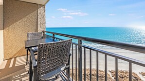 A balcony with a table and chairs overlooking a beach. - Beach Cove condo with balcony & beach access (North Myrtle Beach)