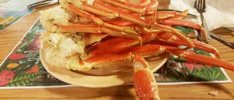 A wooden table with a plate of crab legs and a floral placemat.