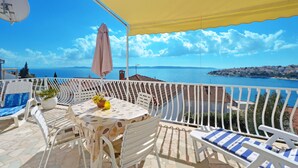 A terrace with white furniture, a table with a yellow umbrella, and a view of the sea. - SOLEA - 2 bedroom sea view apartment 100m from the beach in Okrug Gornji (Okrug Gornji)