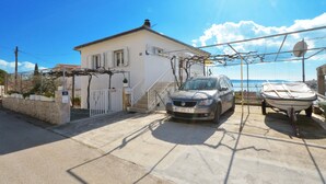 A house with a car parked in front and a boat on a trailer nearby. - SOLEA - 2 bedroom sea view apartment 100m from the beach in Okrug Gornji (Okrug Gornji)