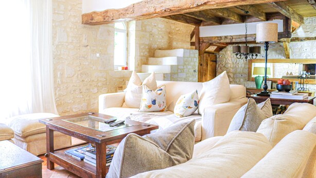 A cozy living room with a stone wall, a wooden ceiling, and a sofa with patterned cushions. - Loire Valley year-round country loft near Chinon (Assay)