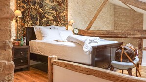 A bedroom with a large bed, wooden headboard, a tapestry on the wall, and a small table with a lamp. - Loire Valley year-round country loft near Chinon (Assay)