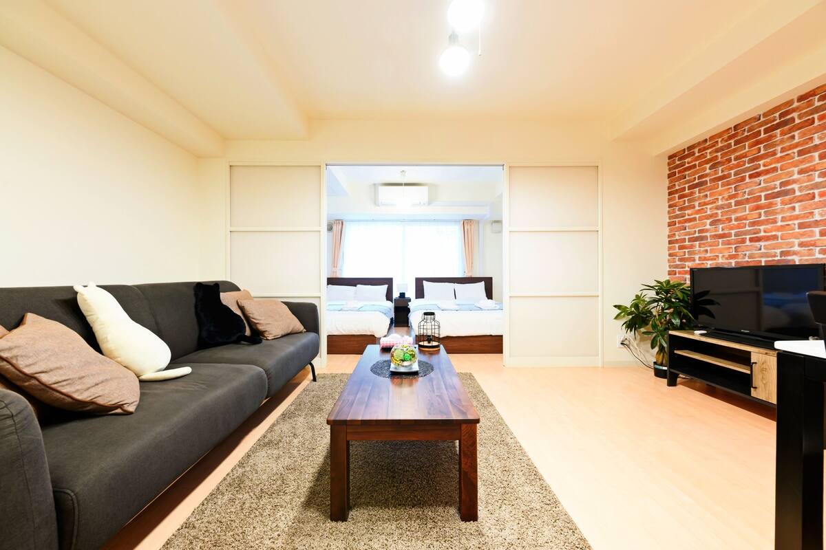 A modern living room with a dark sofa, a wooden coffee table, and a TV stand with a flat-screen TV.