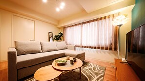 Un salon avec un canapé, une table basse, un téléviseur et une plante.