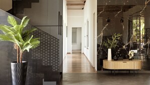 Un intérieur moderne comprenant un escalier, un couloir et un coin repas avec une table ronde et des plantes.