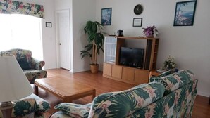 A living room with a sofa, a coffee table, a TV stand, and a potted plant. - Lake Therapy, Experience the ultimate vacation getaway in vibrant Caggans Crossing. (Clermont)