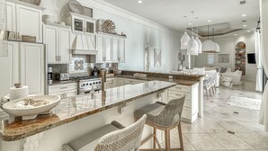 Una cocina amplia con armarios blancos, una isla grande y taburetes de bar.