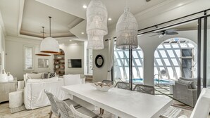 Una cocina moderna con armarios blancos, una isla grande y lámparas colgantes.