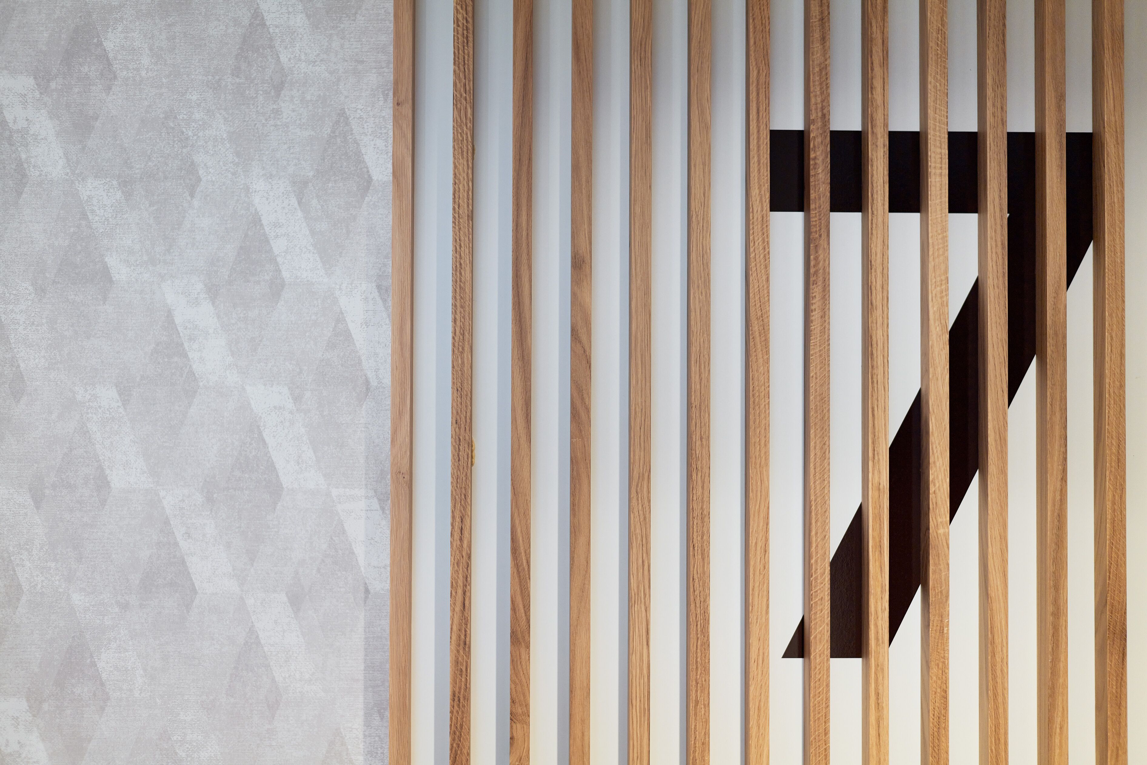 Ein modernes Interieur mit vertikalen Holzleisten und einer Wand mit geometrischem Muster.