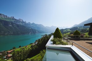 A panoramic view of a mountainous landscape with a lake, a swimming pool, and a well-maintained garden. - Hotel Neu-Schönstatt (Quarten)
