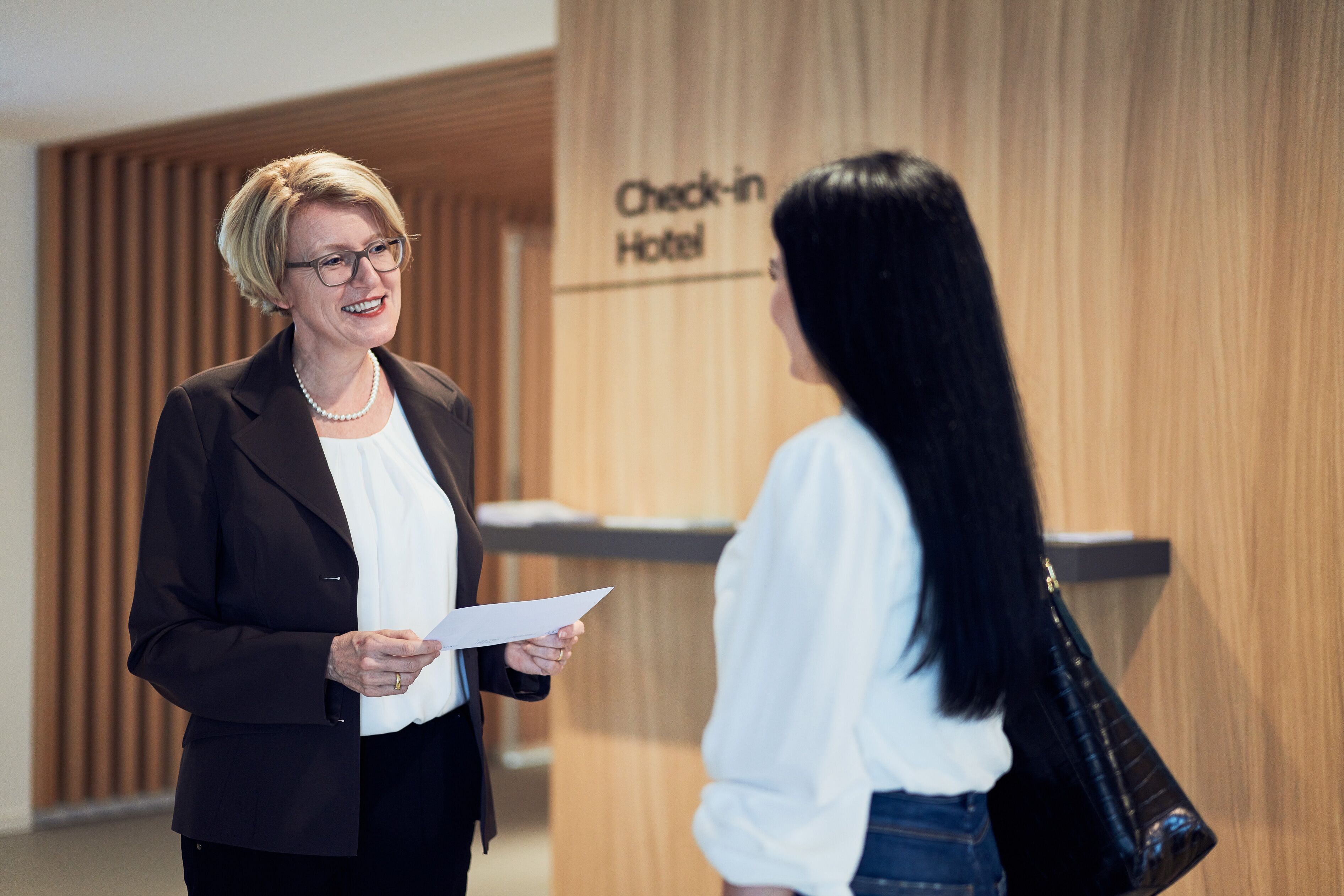 Two people in a hotel lobby with a 'Check-in Hotel' sign.