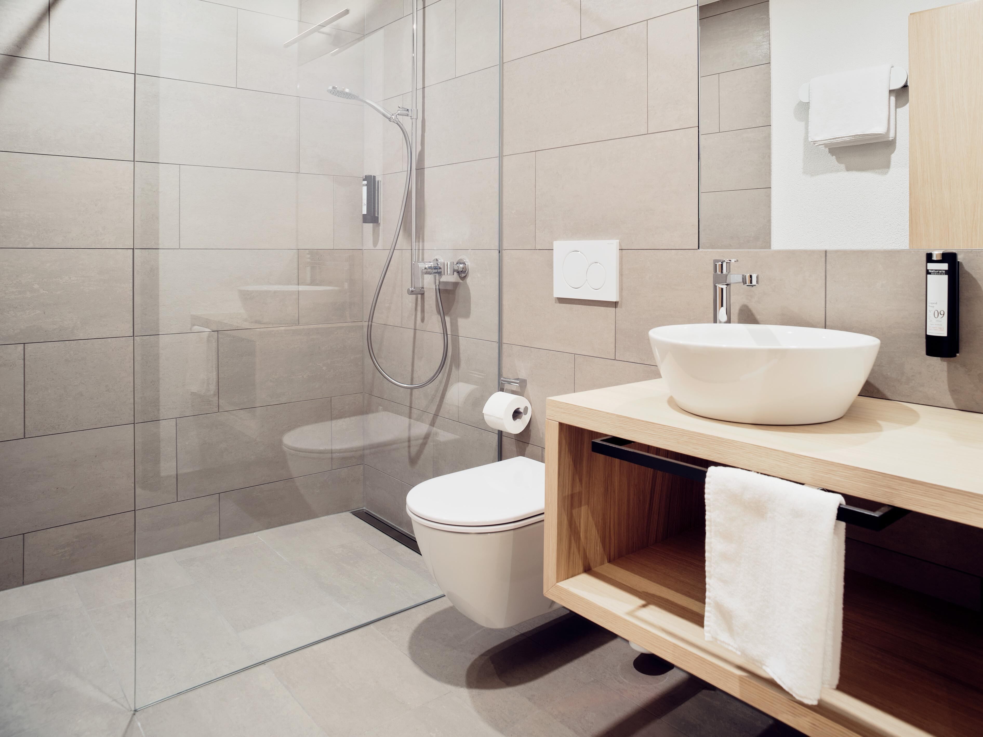 Un baño moderno con ducha de vidrio, inodoro y lavabo de gran tamaño.
