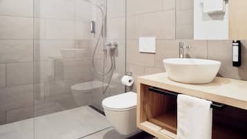 Un baño moderno con ducha de vidrio, inodoro y lavabo de gran tamaño.