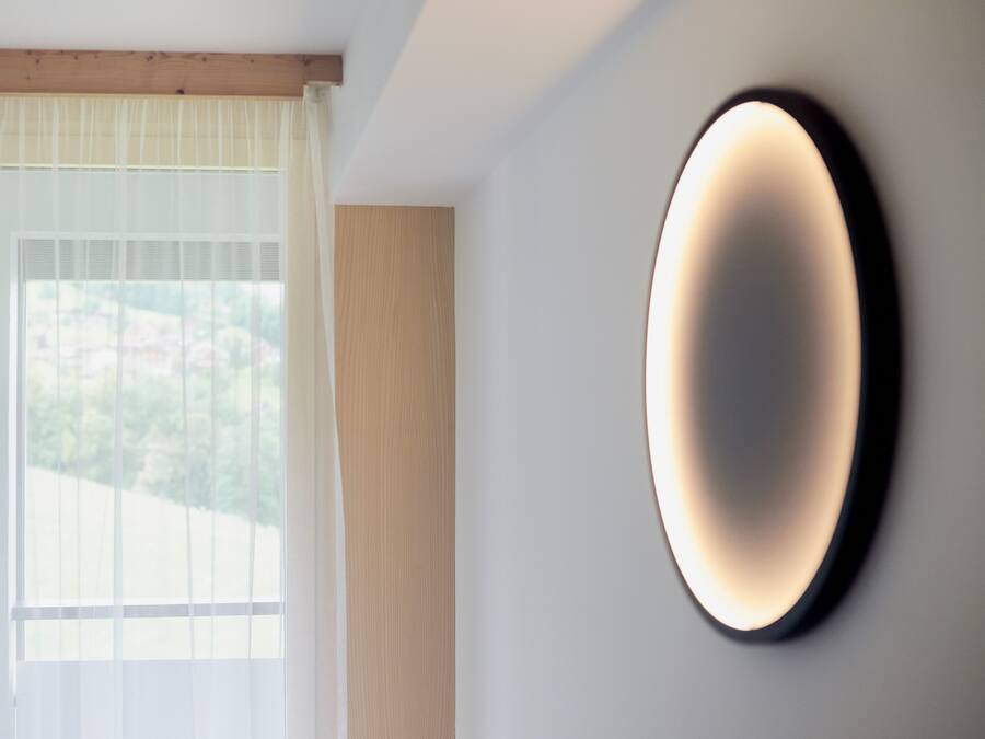 Ein modernes Interieur mit einem großen Fenster, einer Wandleuchte und einer Holzvertäfelung.