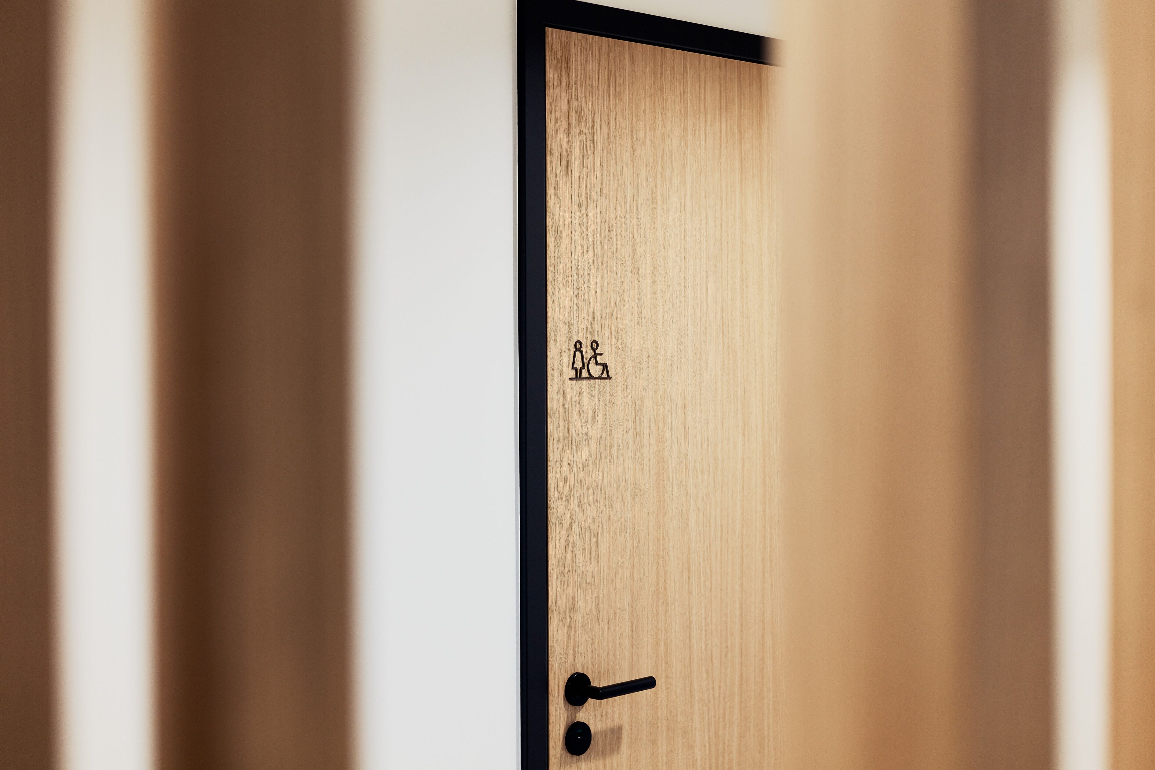 A wooden door with a wheelchair accessibility symbol and a black door handle.