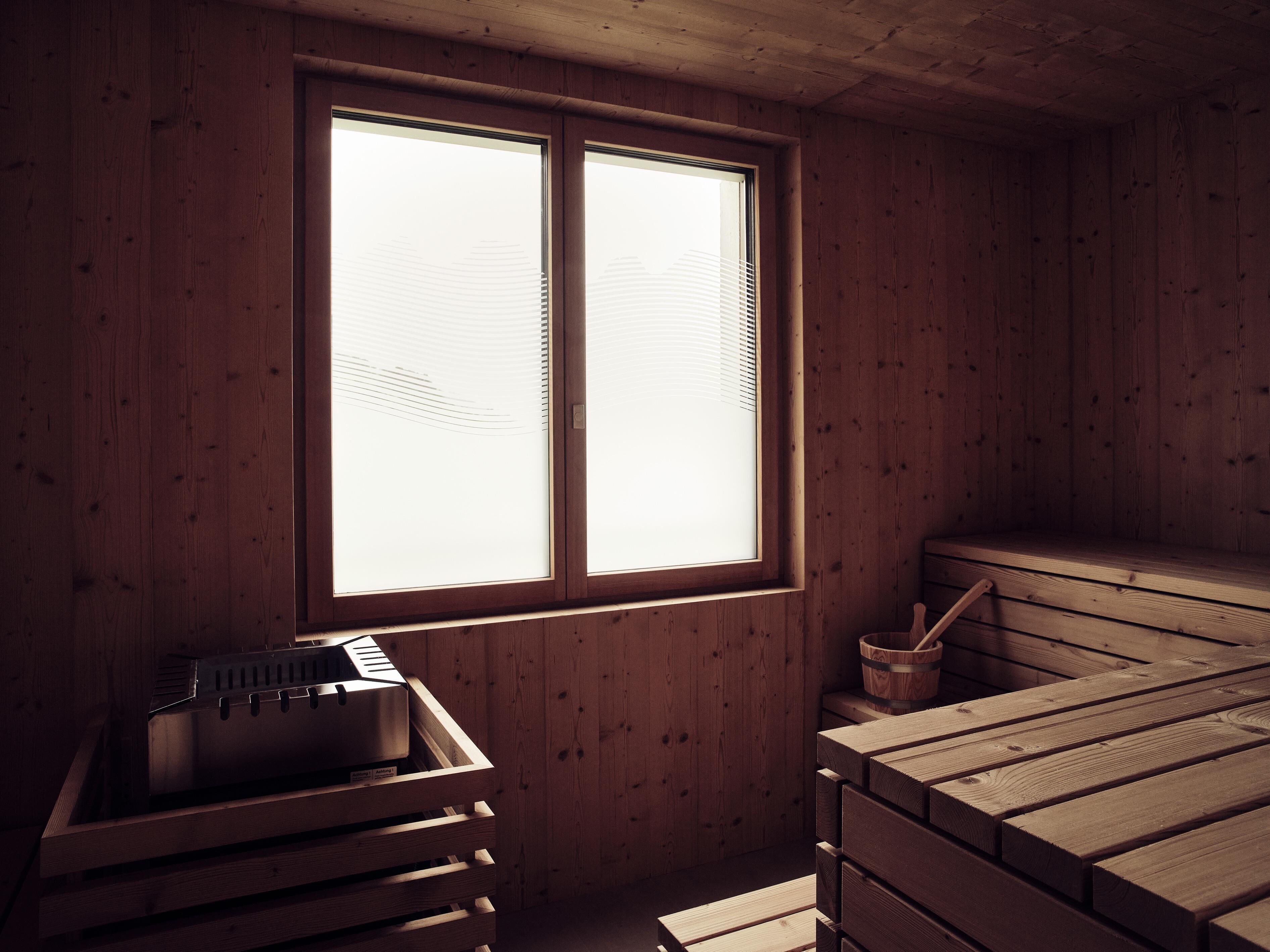 Une pièce en bois avec une grande fenêtre, un sauna et des bancs en bois.