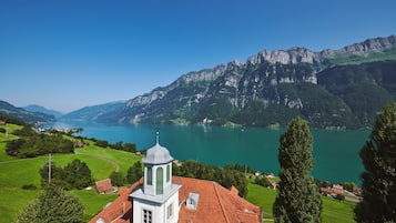 A church with a bell tower overlooking a lake and mountains.