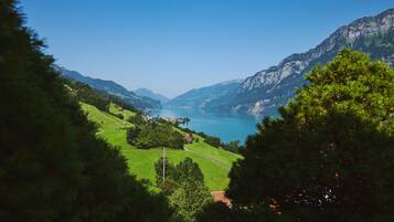 Un paysage montagneux avec un lac, entouré de verdure et de quelques bâtiments.