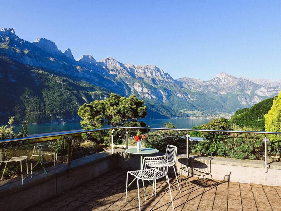 Una terraza con mobiliario exterior, con vistas a un paisaje montañoso y un lago.