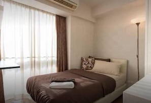 A hotel room with a bed, a bedside table, a lamp, and a window with curtains. - My Resort BKK (Bangkok)