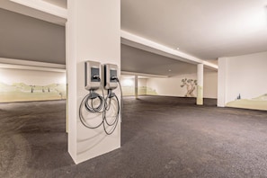 Ein überdachter Parkbereich mit zwei Ladestationen für Elektrofahrzeuge, einem Betonboden und einem Wandgemälde.