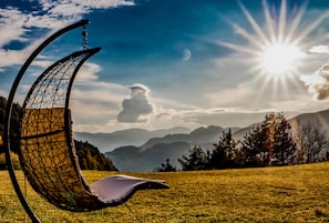 Une chaise au design géométrique, placée dans un champ verdoyant, avec des montagnes en arrière-plan.
