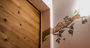 Une porte en bois surmontée d’une enseigne en forme de branche sur laquelle on peut lire : « Paradis ».