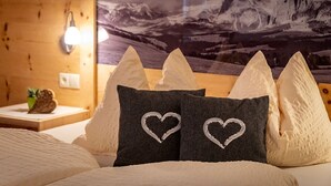 A bedroom with a mountain landscape mural, a wooden headboard, and pillows with heart designs.