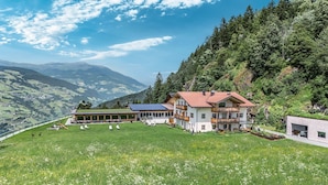 A mountain lodge with a large lawn, multiple balconies, and solar panels.