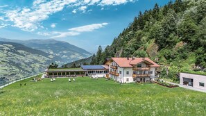 A mountain lodge with a large lawn, multiple balconies, and solar panels.
