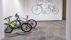 Ein Flur mit einem an der Wand befestigten Schild, das 'Bike Box' zeigt, und zwei Fahrräder, die an der Wand lehnen.