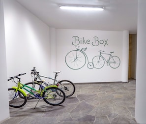 Un couloir avec une enseigne fixée au mur indiquant « Local à vélos » et deux vélos appuyés contre le mur.
