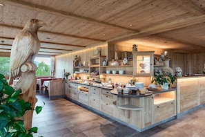 Une cuisine spacieuse avec des meubles en bois, un îlot central et un grand plafond en bois.
