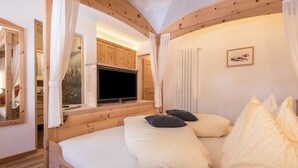 Ein Schlafzimmer mit einem hölzernen Bett, einem Fernseher und einem Fenster mit Vorhängen.