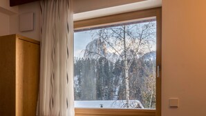 A room with a large window, wooden wardrobe, and a wall-mounted light switch. - Cosy Apartment “Ulrica” with Mountain View, Wi-Fi, Balcony & Terrace (St. Ulrich / Gröden)