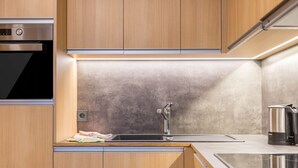 A modern kitchen with wooden cabinets, a stainless steel sink, and a built-in oven. - Cosy Apartment “Ulrica” with Mountain View, Wi-Fi, Balcony & Terrace (St. Ulrich / Gröden)