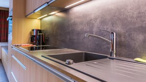 Een moderne keuken met een roestvrijstalen spoelbak, een koffiezetapparaat en houten keukenkastjes.