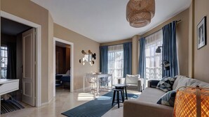 A modern living room with a sofa, a dining table, and a kitchen area.